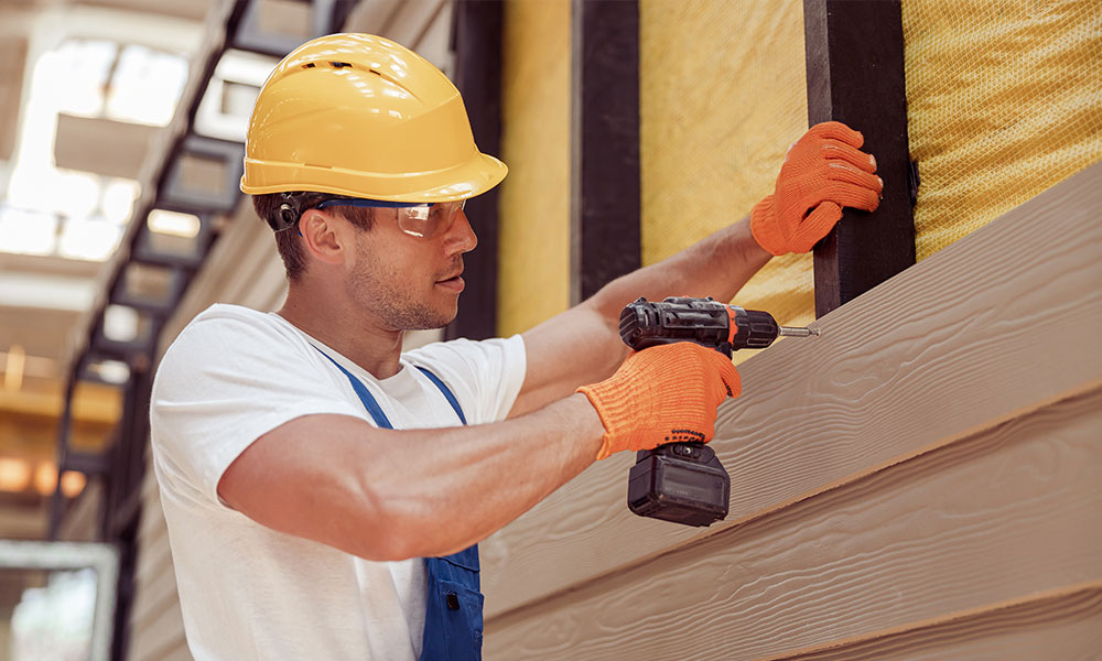 Construction worker installing durable siding for a project by Wolf River Construction, ensuring quality and energy efficiency.