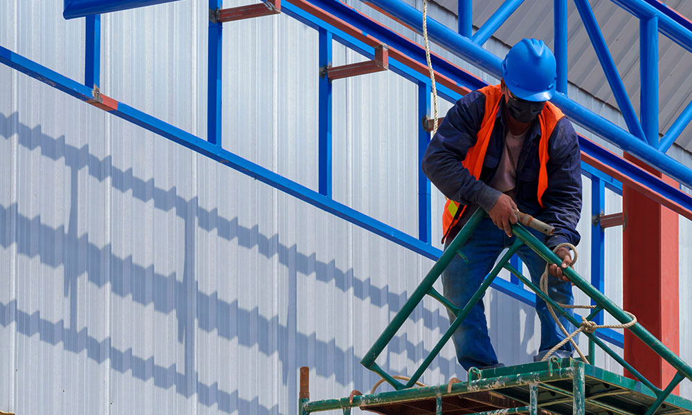 Construction worker installing metal siding for a commercial project by Wolf River Construction, emphasizing quality and durability.